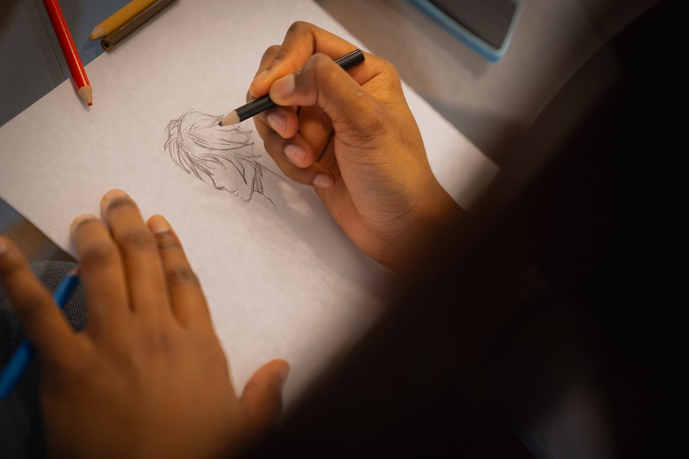Détail d’une main qui dessine au crayon sur une feuille