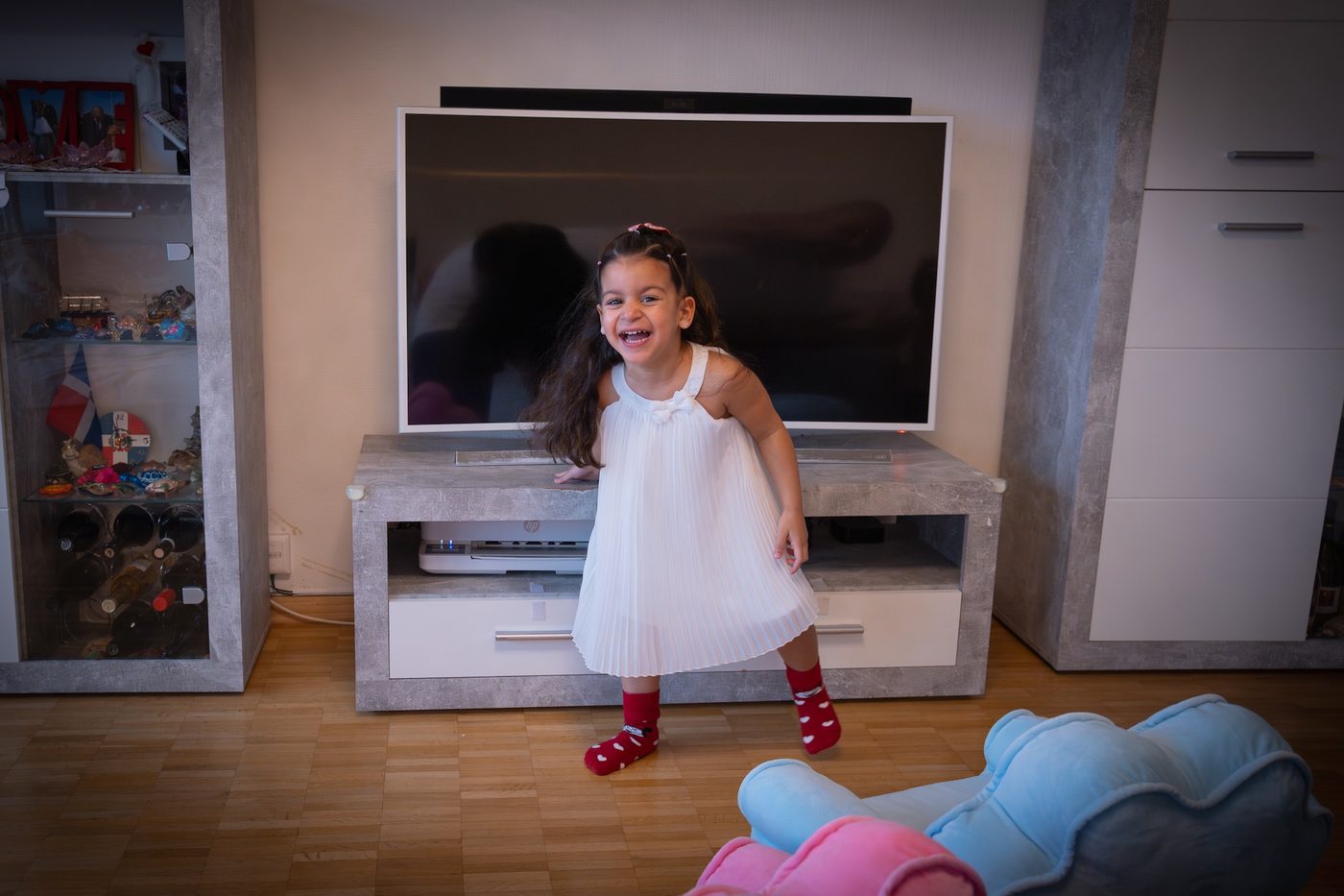 Une petite fille en robe blanche rit dans le salon