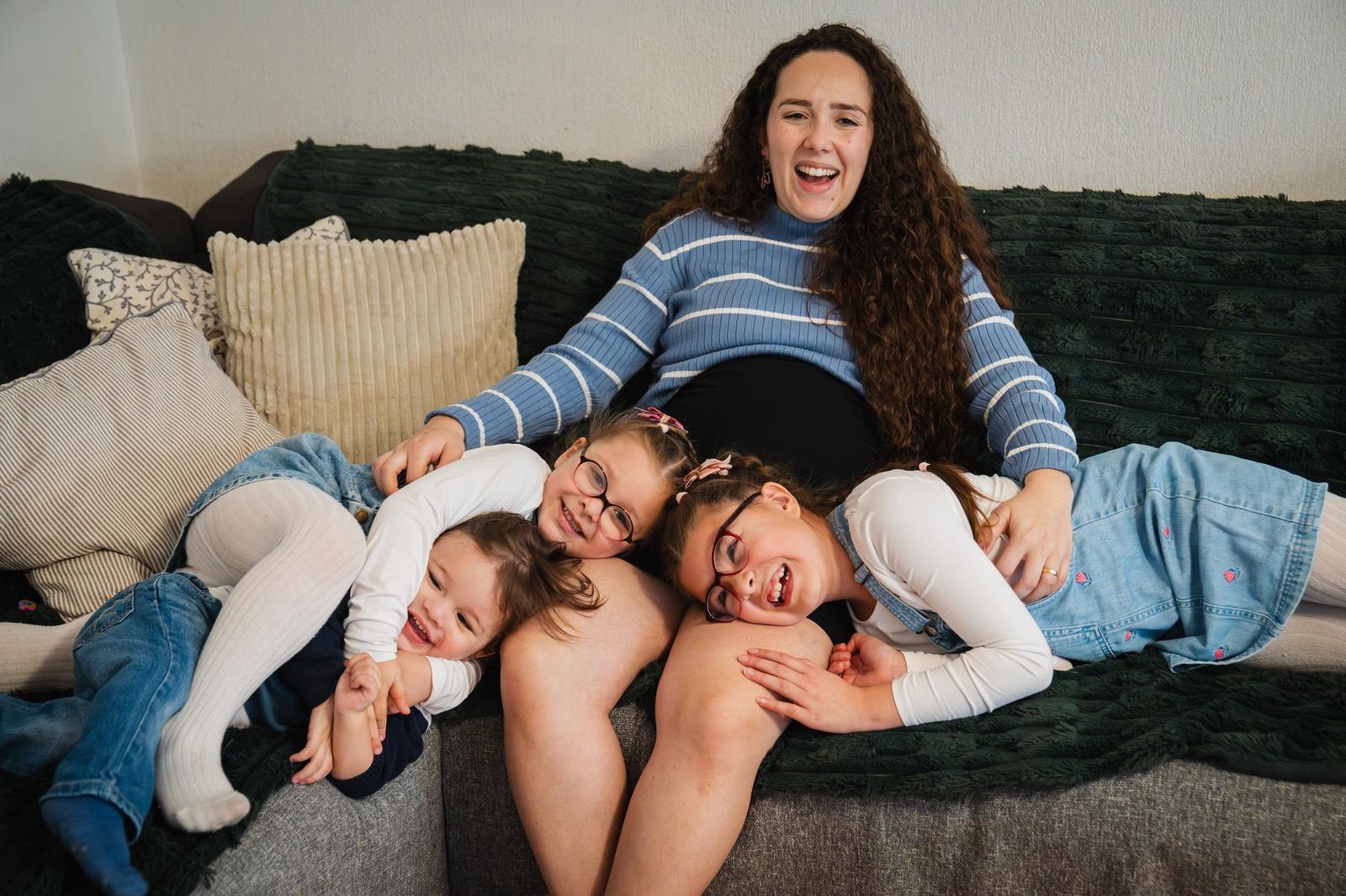 Une famille entière rit en s’empilant sur le canapé
