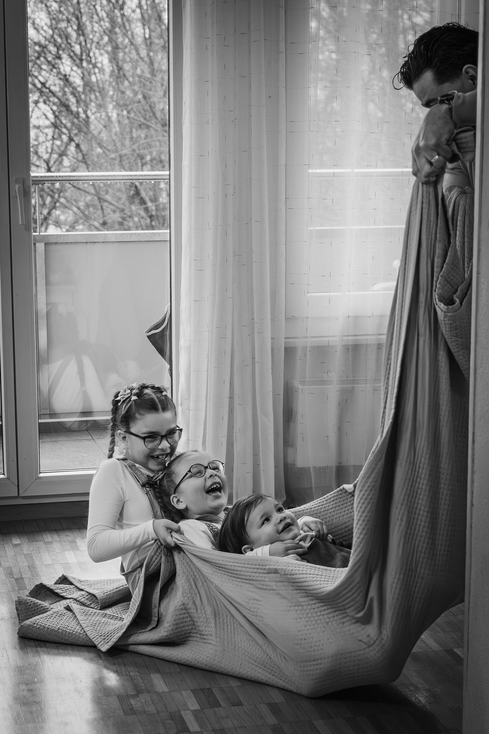 Des enfants jouent dans une grande couverture, photo en noir et blanc