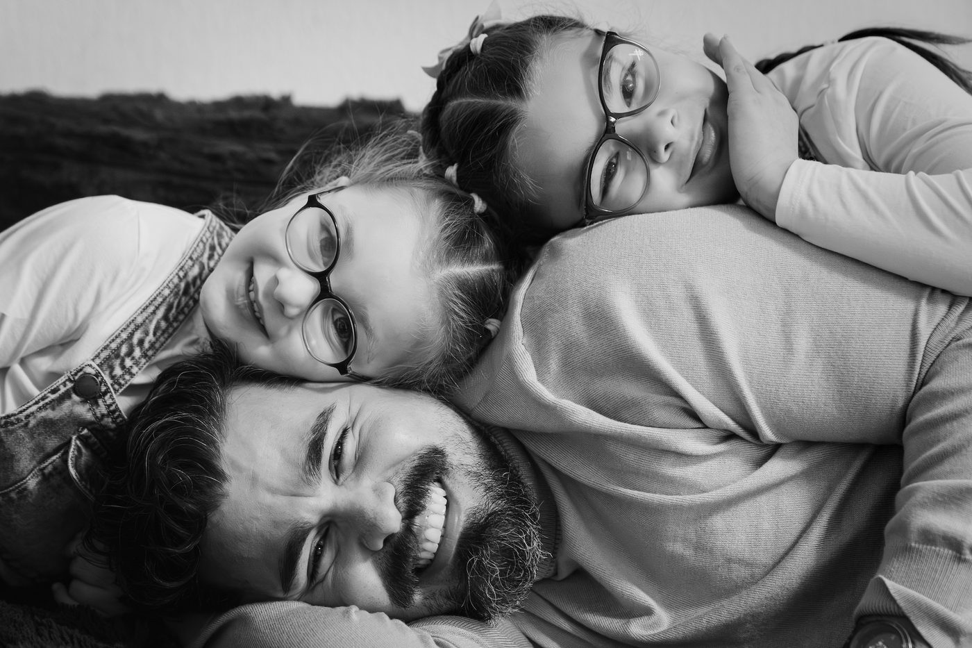 Un père et ses deux filles rient ensemble, photo en noir et blanc