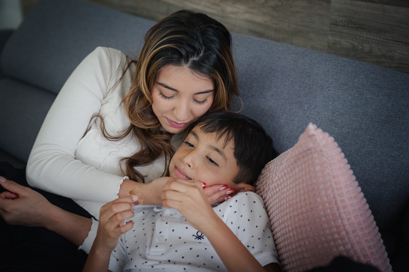 Une maman serre son fils contre elle sur le canapé