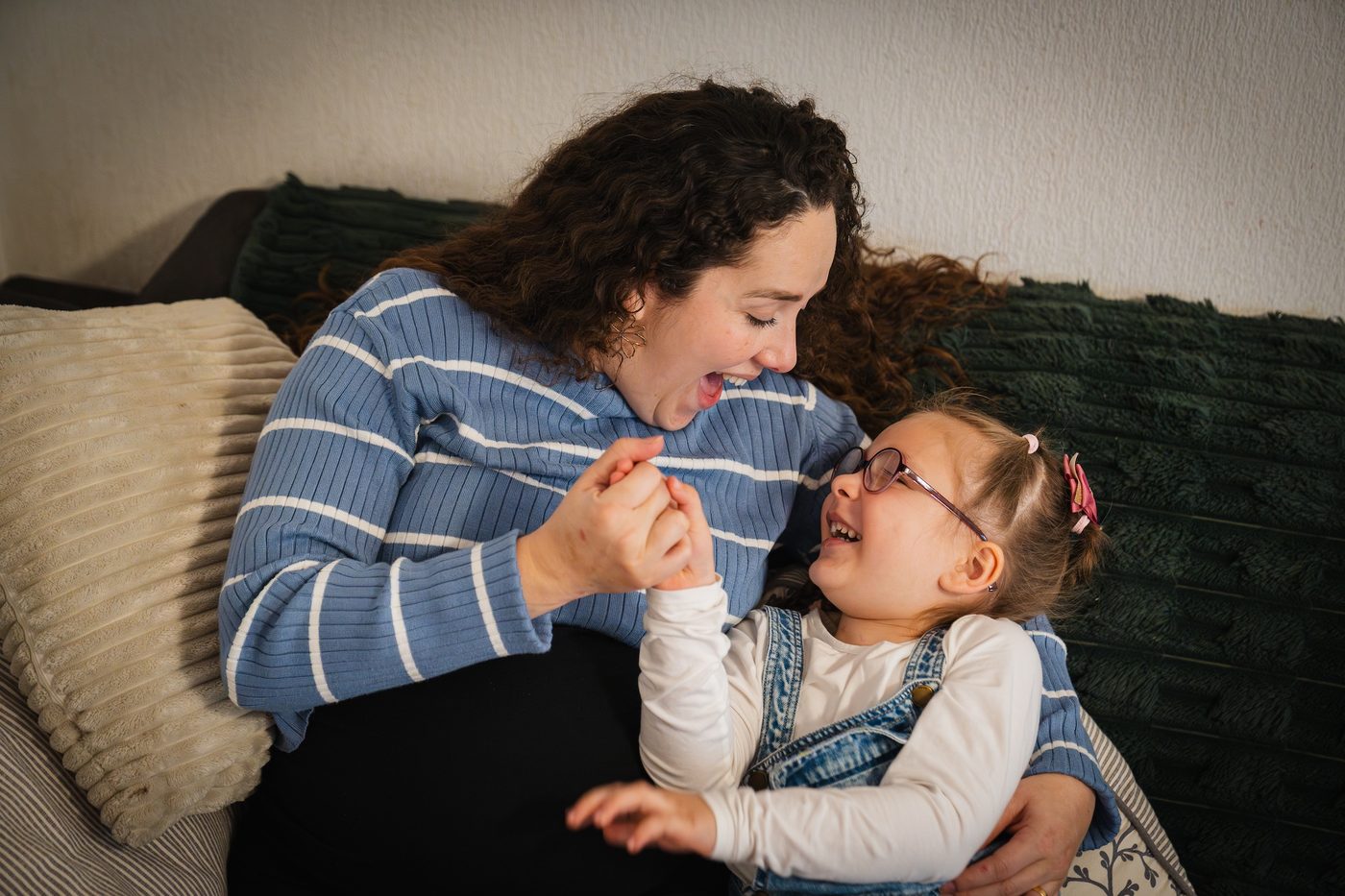 Une maman et sa fille rient ensemble sur le canapé